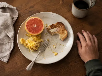 A half-eaten breakfast pushed aside on a wooden table, showing the appetite-suppressing effect of GLP-1 medications like Wegovy