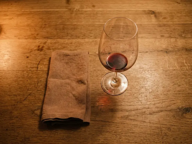 An empty wine glass on a wooden table in dim evening light, representing the alcohol that quietly disrupts deep sleep.