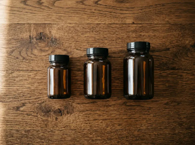 Three unlabeled amber supplement bottles on a wooden table, representing different forms of iron and their tolerability.